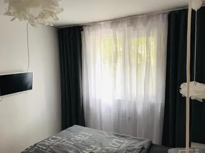 a bedroom with a bed and a window with curtains at Вила ОмниЯ in Chernomorets