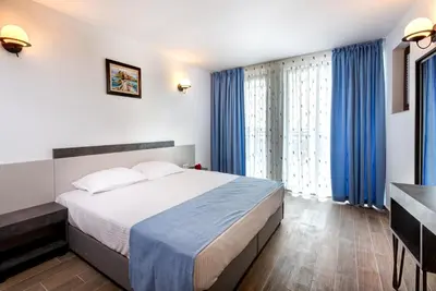 a bedroom with a large bed with blue curtains at Panorama Blue Family Hotel and Free parking in Nesebar