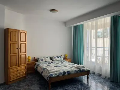 a bedroom with a bed and a large window at Студио Одеса 22 in Sozopol