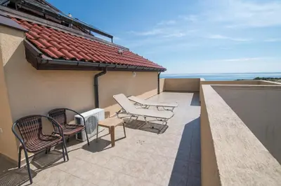 a patio with chairs and a heater on a roof at ТРОПИКАНА in Primorsko