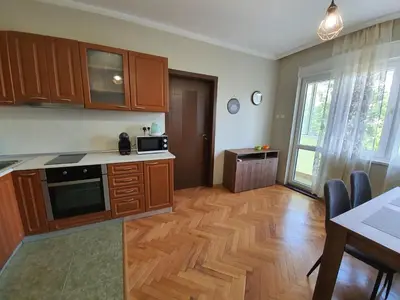 a kitchen with wooden cabinets and a wooden floor at Danny apartment in Burgas City