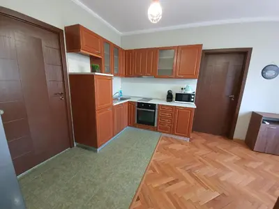 an empty kitchen with wooden cabinets and wooden floors at Danny apartment in Burgas City