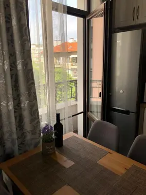 a bottle of wine sitting on a table next to a window at Sunny Shore Burgas Apartment in Burgas City