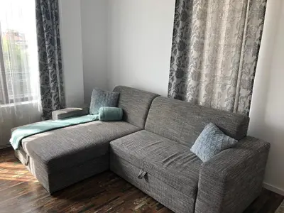 a gray couch in a living room with a window at Sunny Shore Burgas Apartment in Burgas City