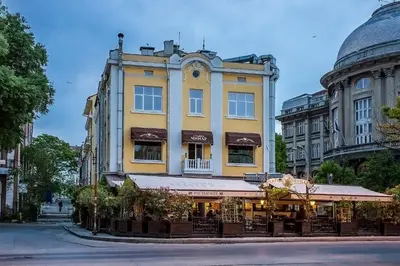 a yellow building with a restaurant in front of it at Deluxe studio Center city in Varna City