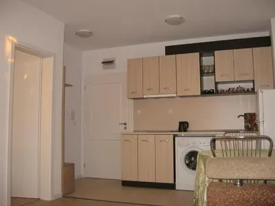 a kitchen with wooden cabinets and a washer and dryer at Айвазовский парк in Pomorie