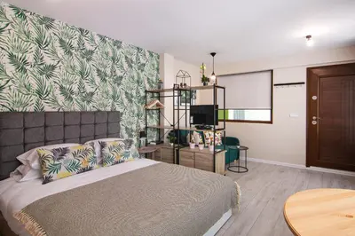 a bedroom with a bed and a wall with a leafy wallpaper at The Cozy Studio, Varna City Centre in Varna City
