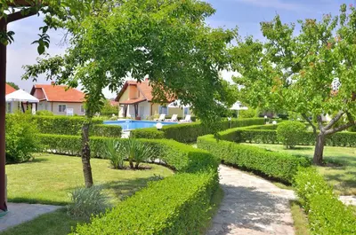 a garden with hedges and a swimming pool at BulgariaVilla - Sunny Hills Villas in Bryastovets