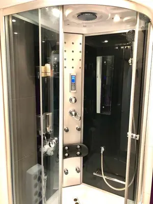 a bathroom with a shower with a sink and a mirror at Avelov Art Apartment in Burgas City
