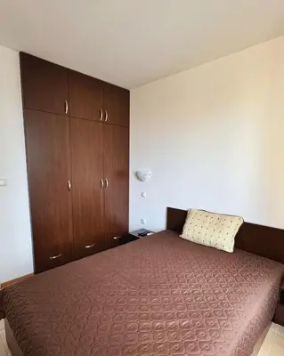 a bedroom with a bed and wooden cabinets at Marina Bay Apart Saint Vlas in Sveti Vlas