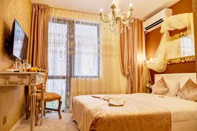 a bedroom with a bed and a desk and a window at Hotel IMPERIA in Varna City