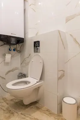 a bathroom with a toilet and a tv on the wall at Comfy home in the heart of Burgas in Burgas City