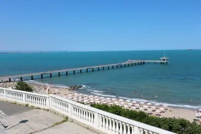 a beach with umbrellas and a pier in the water at Comfy home in the heart of Burgas in Burgas City