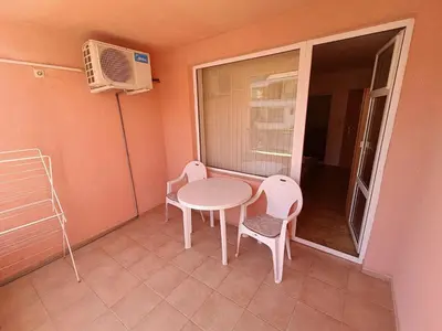a small balcony with a table and chairs and a window at Tony Guest House in Sozopol
