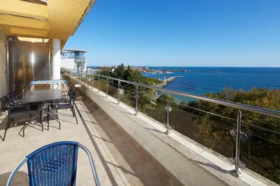 a balcony with a table and chairs and the ocean at Infinity Terrace 1BR Apartment Nessebar in Nesebar