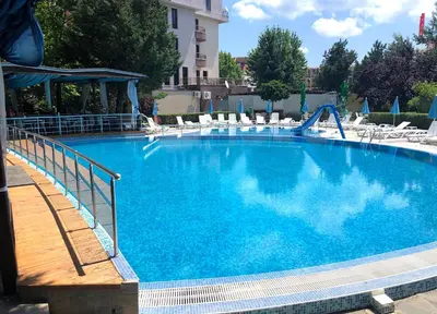 a large blue swimming pool with chairs and a slide at Hotel Pacific Palma in Sunny Beach