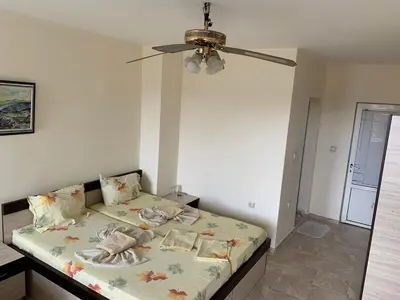 a bedroom with a bed with a ceiling fan at Guest Rooms Nia Elis Kiten in Burgas City