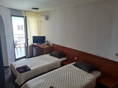 a hotel room with two beds and a television at Алми Almi in Sveti Vlas