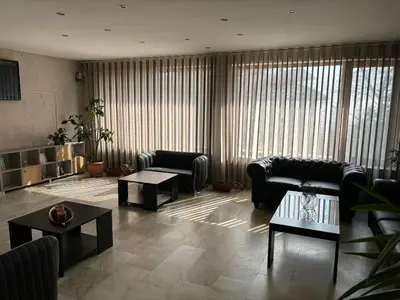 a living room with couches and tables and windows at Relax Guest House in Burgas City