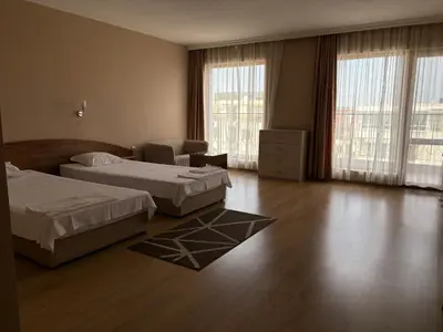 a hotel room with two beds and a chair at Relax Guest House in Burgas City