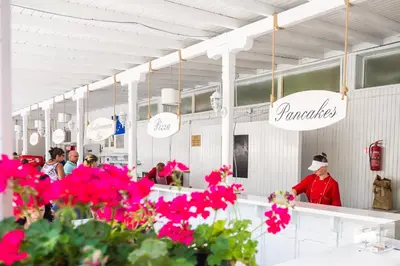 a restaurant with pink flowers in front of a counter at Sun Palace Hotel - All Inclusive in Sunny Beach