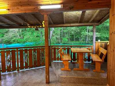 a wooden porch with a wooden table and benches on a deck at “River Romance” Villa in Kamchia