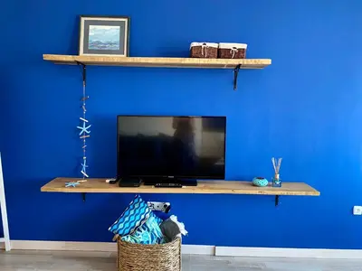 a blue wall with a tv on a wooden shelf at Свети Зосим in Sozopol