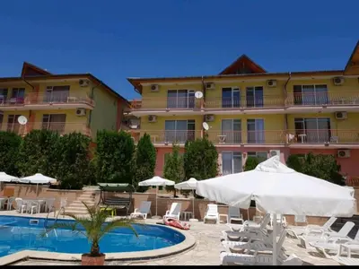 a hotel with a pool and chairs and an umbrella at Курортно студио in Sunny Beach