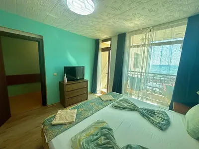 a bedroom with a bed with a television and a window at Апартаменти Зафи in Sozopol