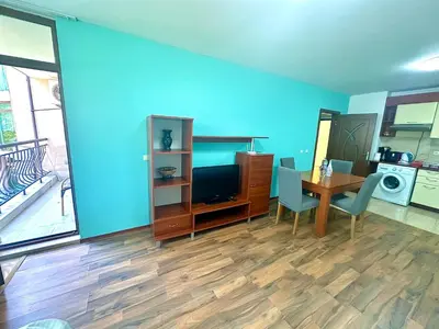 a living room with a dining room table and a blue wall at Апартаменти Зафи in Sozopol