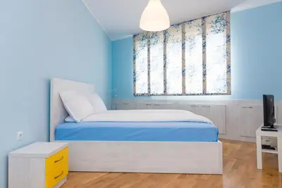 a blue bedroom with a bed and a television at Апартамент в жълто in Burgas City