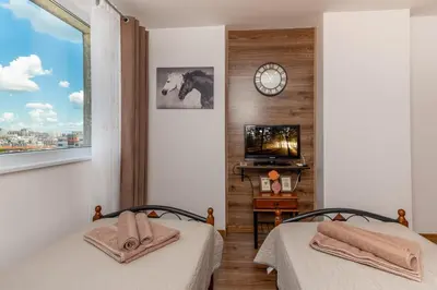two beds in a room with a clock on the wall at Апартамент за гости ВО1 in Burgas City