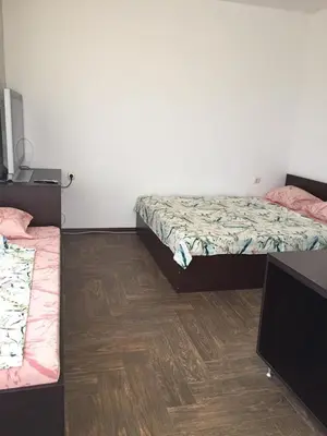 a room with two beds and a wooden floor at Къща за гости ЕЛИ in Primorsko