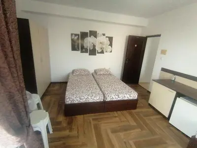 a small bedroom with a bed and a wooden floor at Къща за гости ЕЛИ in Primorsko