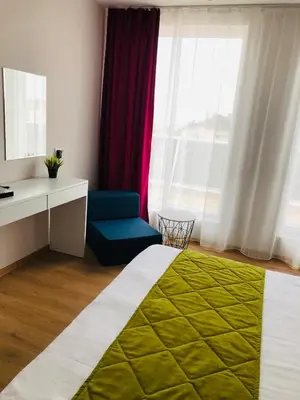 a hotel room with a bed and a chair and window at Colors Boutique in Obzor