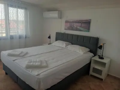 a bedroom with a large bed with white sheets at Vila Rosen in Lozenets
