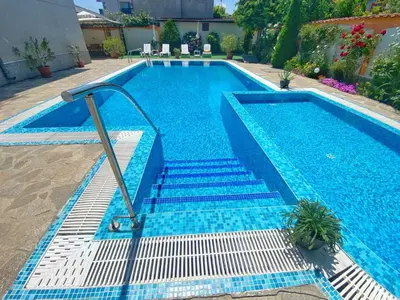 a swimming pool with blue tiles and stairs next to a house at Vila Rosen in Lozenets