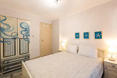 a white bedroom with a bed and two lamps at Guest House Soirée in Nesebar