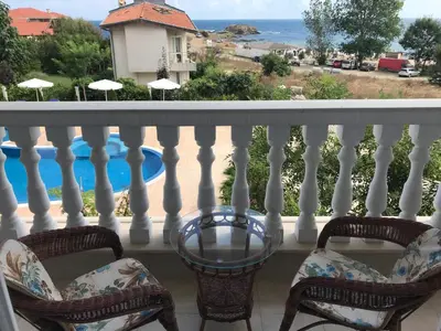 a balcony with chairs and a table and a swimming pool at Студио Сънрайз А28, Лозенец in Lozenets