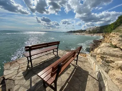 a bench sitting on the edge of a cliff overlooking the ocean at Sea View Panoramic Apartments, Fort Noks Crown Club in Sveti Vlas