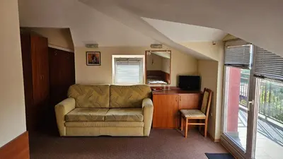 a living room with a couch and a table and a television at Caprice Family Hotel in Varna City