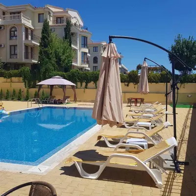 a pool with chairs and umbrellas next to a building at Horizon Katrina Apartments - Sea line & Beach Access in Sveti Vlas