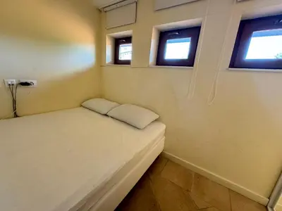 a small bed in a room with two windows at Santa Marina resort Sozopol - penthouse with amazing sea view in Sozopol