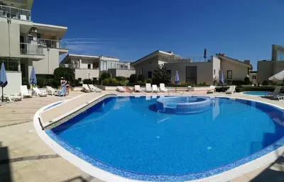 a large blue swimming pool with chairs and buildings at Wonderful family villa with sea view in Byala