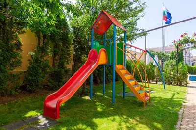 a playground with a slide in the grass at Hotel Julia in Sveti Vlas
