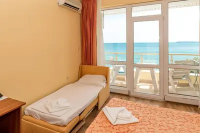 a room with a bed and a balcony with the ocean at Iris Beach Hotel in Sveti Vlas