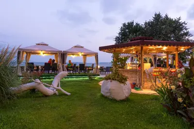 a garden with a gazebo and people sitting on the grass at Iris Beach Hotel in Sveti Vlas