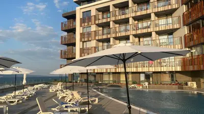 a pool with chairs and umbrellas in front of a building at PARADISO 'В' 310 Private Room Nessebar in Nesebar