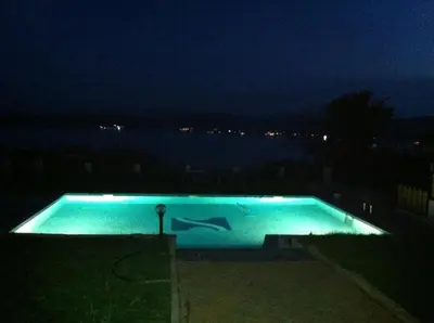 a swimming pool at night with a view of the water at Safo Apartments and Rooms in Sozopol