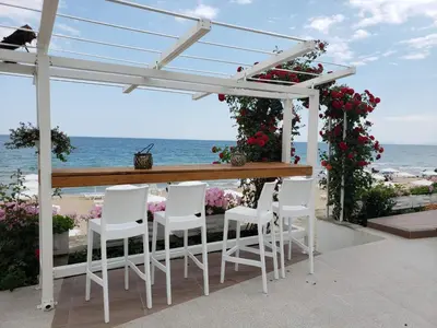 a bar with white chairs and a view of the ocean at Perla Apartments First Line in Nesebar